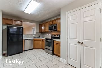 Baytown house for rent - A kitchen with a black fridge and wooden cabinets.
