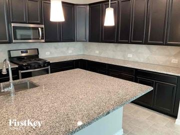 Haslet house for rent - A kitchen with granite countertops and black cabinets.