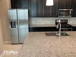 Haslet house for rent - A kitchen with granite countertops and a stainless steel refrigerator.