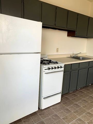 Homestead apartment for rent - A white refrigerator is in a kitchen with a white stove and green cabinets.