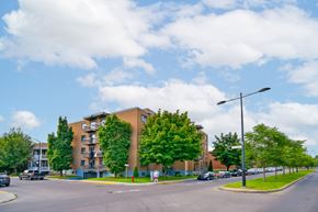 Montréal apartment for rent - A street view of a residential area with apartment buildings and parked cars.