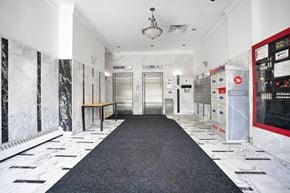 Montréal apartment for rent - A hallway with a black carpet and marble walls.
