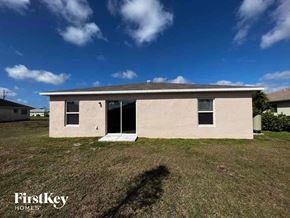 Cape Coral house for rent - front view of a small tan house on a grass field