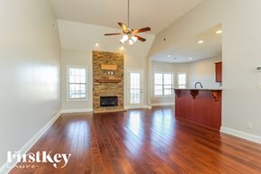 Clarksville house for rent - A spacious room with wooden floors and a stone fireplace.