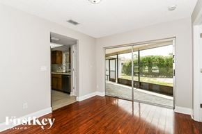 Fort Myers house for rent - A room with a wooden floor and a sliding glass door leading to a backyard.