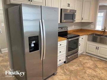 Fleming Island house for rent - a stainless steel refrigerator in a kitchen with white cabinets