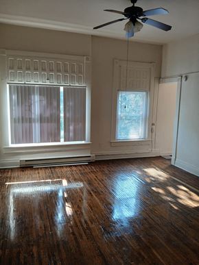 Louisville apartment for rent - an empty living room with a ceiling fan and two windows