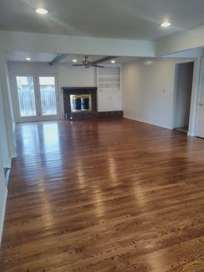 Tulsa house for rent - an empty living room with wooden floors and a fireplace