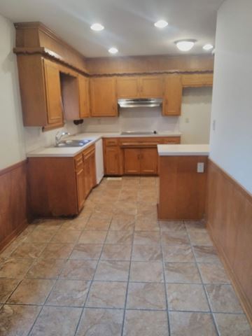 Tulsa house for rent - an empty kitchen with wooden cabinets and tiled floors