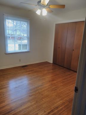 Tulsa house for rent - an empty bedroom with wooden floors and a window