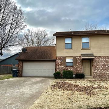 Tulsa house for rent - a tan brick house with a garage and a blue house