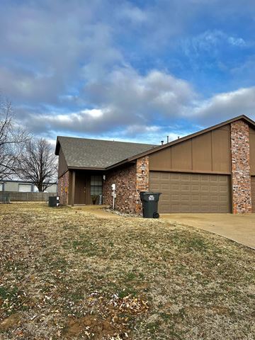 Tulsa house for rent - a brick house with a brown garage and a cloudy sky