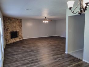 Tulsa house for rent - A room with a stone fireplace and wood flooring.