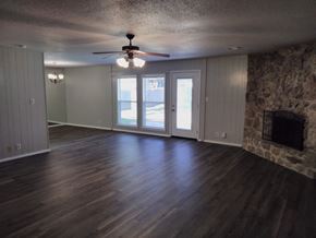 Tulsa house for rent - A room with a ceiling fan and a stone fireplace.