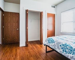 Watford City apartment for rent - A bedroom with a bed, wooden closet doors, and a window with blinds.