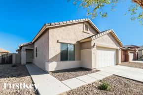Buckeye house for rent - A beige house with a white garage door and a gravel driveway.