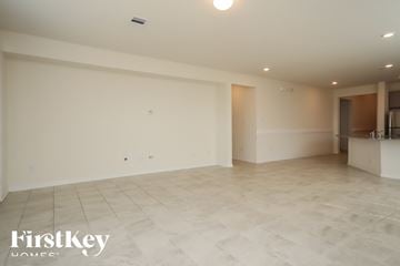 Richmond house for rent - A spacious room with a tiled floor and a kitchen area in the background.