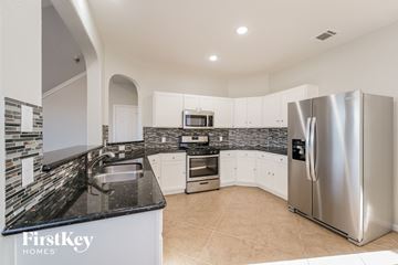 Fresno house for rent - A modern kitchen with a stainless steel refrigerator and a black countertop.
