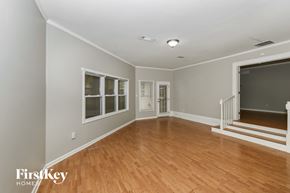 Memphis house for rent - A spacious room with wooden floors and a staircase leading to another room.