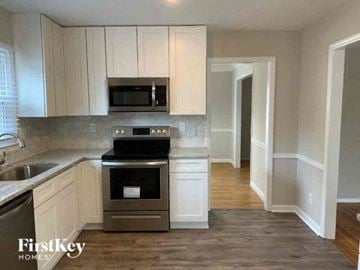 Charlotte house for rent - a kitchen with white cabinets and a stove and a microwave