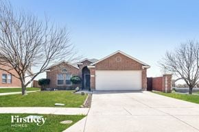 Lavon house for rent - A brick house with a white garage door and a tree in front.