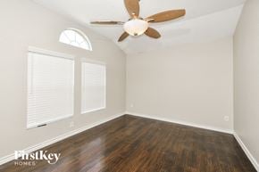 Lavon house for rent - A room with a ceiling fan and wooden floors.