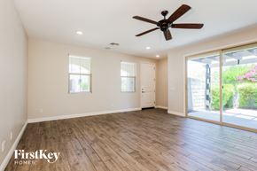 Goodyear house for rent - A spacious room with a ceiling fan and sliding glass doors leading to a garden.