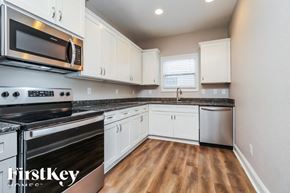 Murfreesboro house for rent - A kitchen with white cabinets and a black stove top oven.
