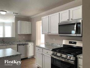 Lithonia house for rent - a kitchen with white cabinets and a stove and a microwave