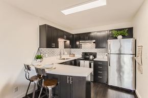 Portland apartment for rent - Downtown Portland, OR, Urban Apartments - Linc 301 - Kitchen with Stainless Steel Appliances, Black and Modern Cabinets, Corian Countertops, and High Chairs.