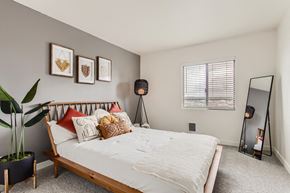 Portland apartment for rent - Downtown Portland, OR, Modern Apartments - Linc 301 - Bedroom with Carpet Flooring, Large, Wooden Bed, Standing Lamp, Full-Body Mirror, Decorative Potted Plant, and Window.