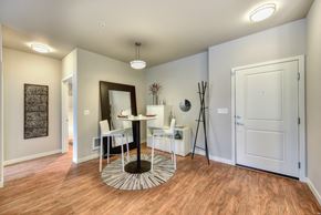 Bellevue apartment for rent - Dining Area and Entryway with Wood Inspired Floors, Tall White Table, White Chairs and Mirror With Black Frame Resting Against Wall