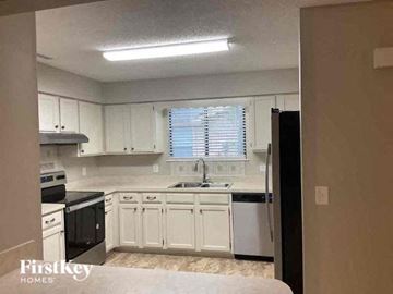 Jacksonville house for rent - an empty kitchen with white cabinets and black appliances