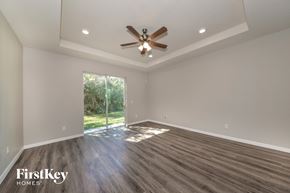 Palmetto house for rent - an empty living room with a ceiling fan and a window