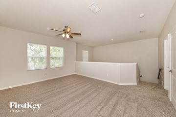 Palmetto house for rent - a spacious living room with carpet and a ceiling fan