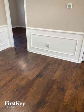 Charlotte house for rent - A wooden floor with a white baseboard and a wall socket.