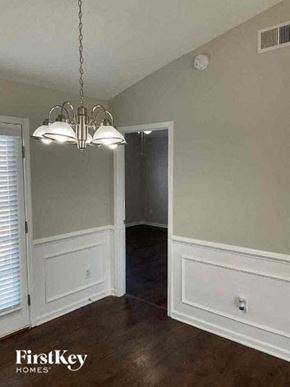 Charlotte house for rent - A chandelier hangs over a white door in a room with wood floors and white walls.