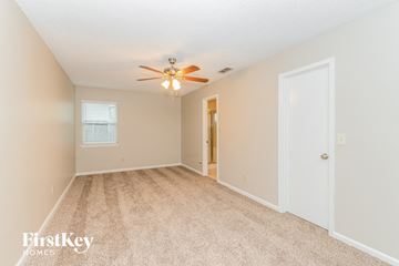Jacksonville house for rent - a spacious living room with beige carpet and a ceiling fan