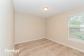 Jacksonville house for rent - a bedroom with a carpeted floor and a large window