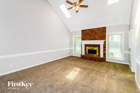 Bartlett house for rent - A spacious room with a fireplace and a ceiling fan.