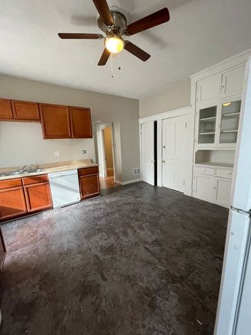 St. Louis apartment for rent - A room with a ceiling fan and a kitchen area with white cabinets.