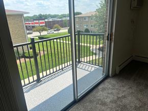 Addison apartment for rent - A view from a balcony looking out at a parking lot and buildings.