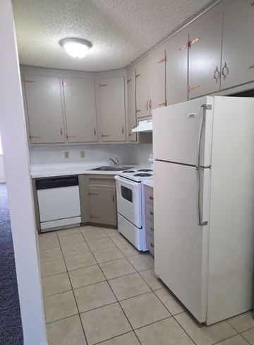 Tulsa apartment for rent - A white refrigerator stands in a kitchen with white cabinets.