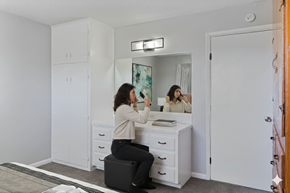 Tulsa apartment for rent - A woman is sitting on a stool in front of a vanity table with a mirror.