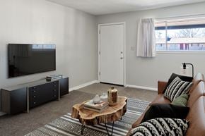 Tulsa apartment for rent - A living room with a brown couch, a wooden coffee table, and a flat screen TV.