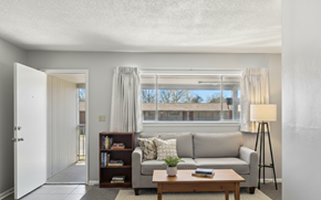 Tulsa apartment for rent - A living room with a grey couch, a wooden coffee table, a bookshelf, and a floor lamp.