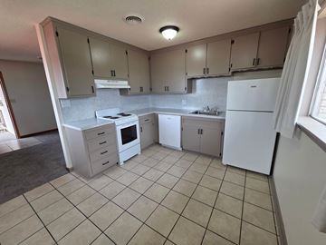 Tulsa apartment for rent - A kitchen with white appliances and beige cabinets.