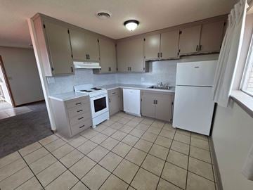 Tulsa apartment for rent - A kitchen with white appliances and beige cabinets.