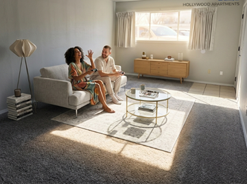 Tulsa apartment for rent - A couple is sitting on a couch in a living room with a coffee table in front of them.