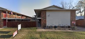 Tulsa apartment for rent - A building with a garage door and a sign in front of it.